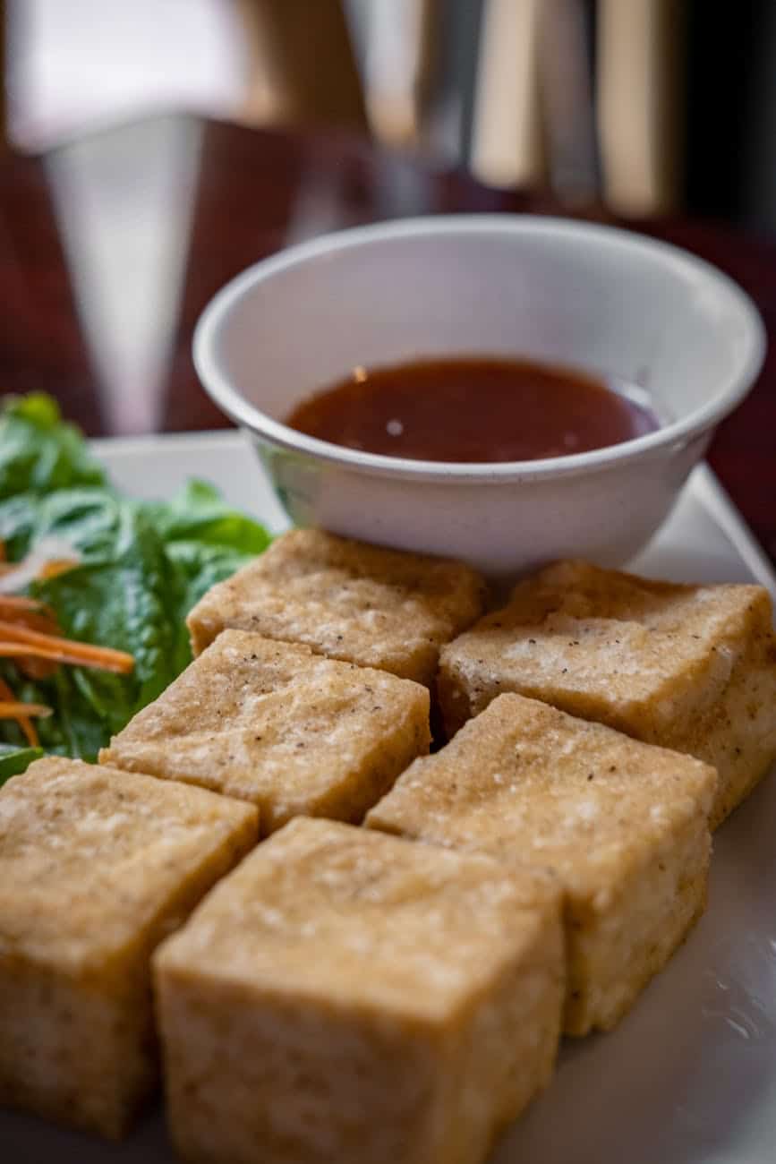 fried tofu cubes and a bowl of sauce on a tray